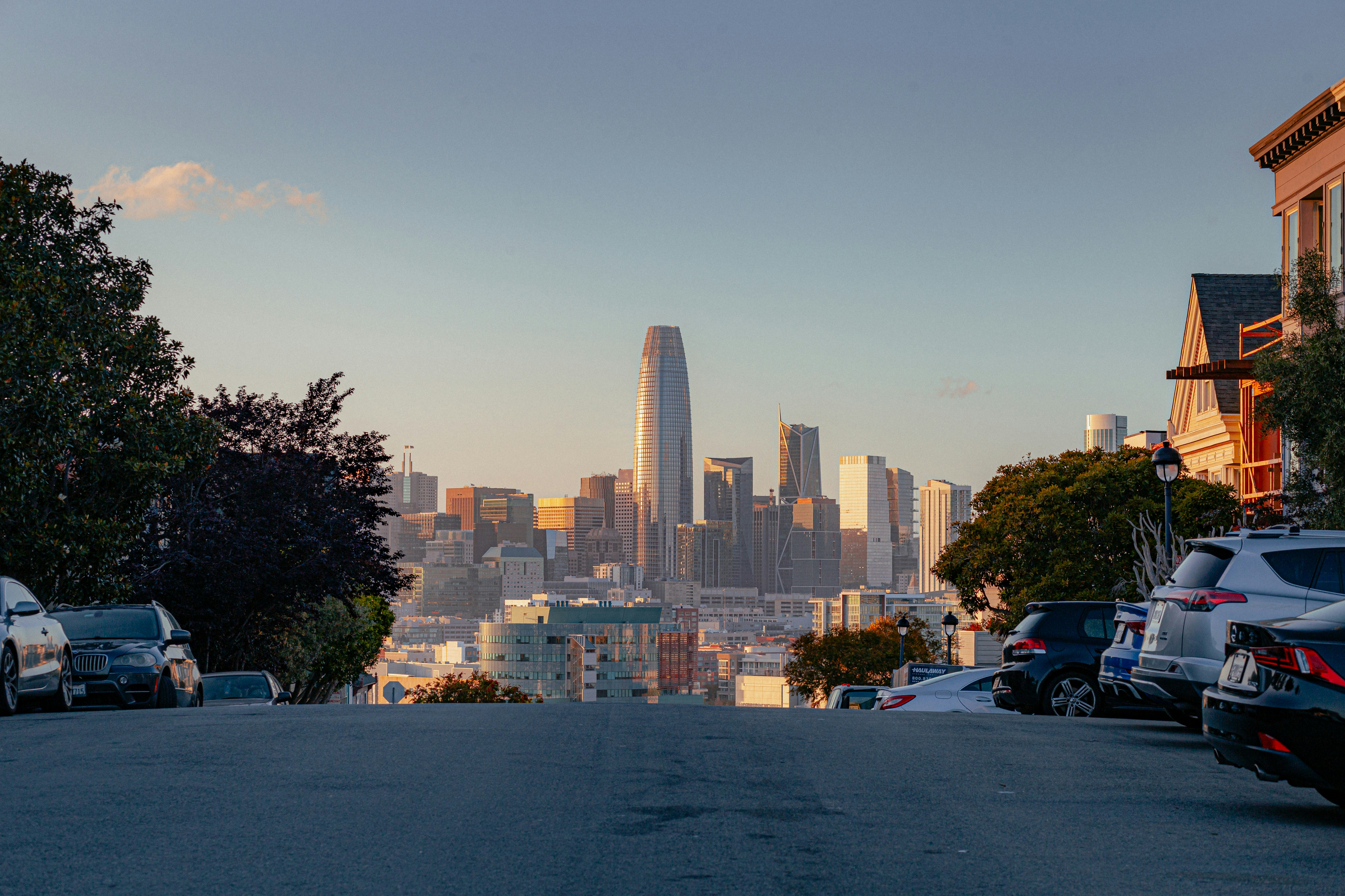 View of the San Francisco skyline at golden hour from a hillside street
